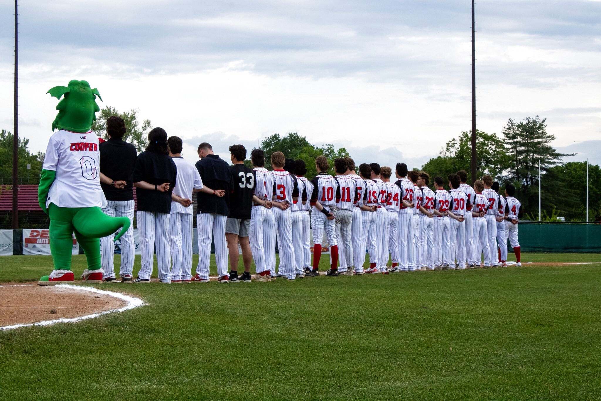 The Glens Falls Dragons lined up along the baseline for the national anthem at East Field, Cooper the Dragon at the end of the row.